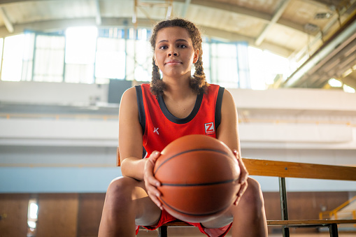 Basketball Training Game Background. Basketball on Wooden Court Floor Close Up with Blurred Players Playing Basketball Game in the Background