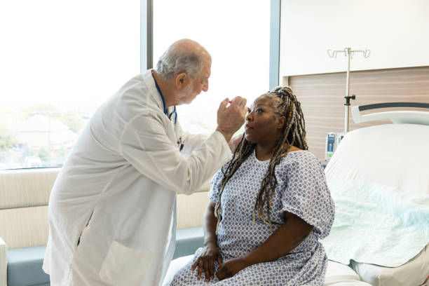 Na ostrym dyżurze starszy lekarz sprawdza dojrzałą kobietę pod kątem wstrząsu mózgu – zdjęcie