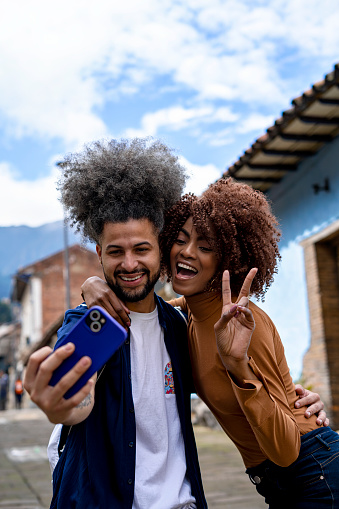 Friends taking selfies with cell phones in the streets of La Candelaria neighborhood in Bogota.