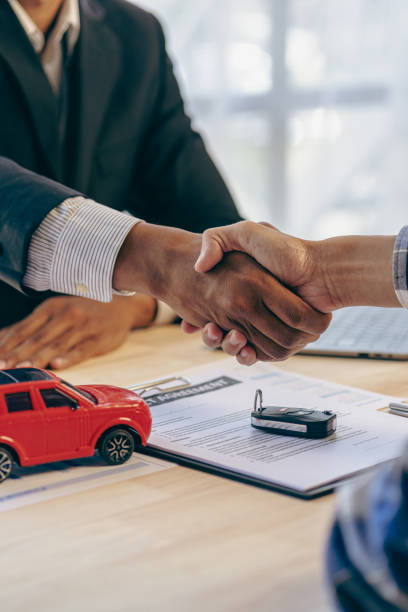 Car dealer or sales manager offers to sell a car and explains terms of car contract signing and insurance handshake after signing contract and paying successfully vertical image stock photo