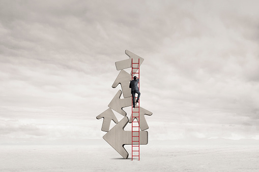 A man climbs a tall ladder that leans against a stack of arrows.