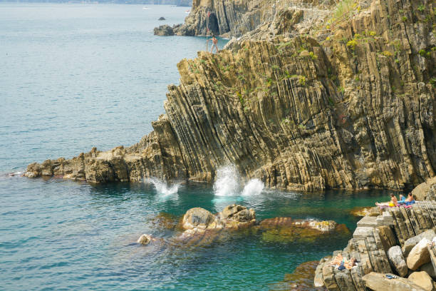 falaise rocheuse bord de mer avec un motif vertical accidenté et patiné plongeant dans l’océan - weatherd photos et images de collection