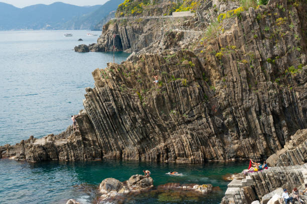 rock cliff sea edge with rugged weatherd vertical pattern plunging into ocean - weatherd imagens e fotografias de stock