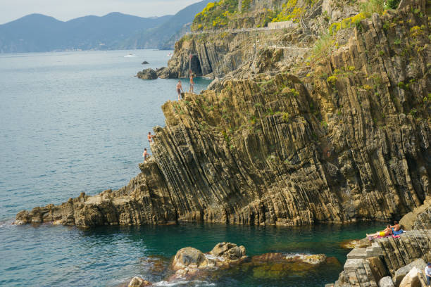 rock cliff sea edge with rugged weatherd vertical pattern plunging into ocean - weatherd imagens e fotografias de stock