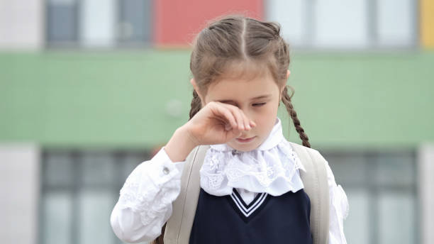 la studentessa junior asciuga le lacrime contro la scuola moderna - bullying sneering rejection child foto e immagini stock