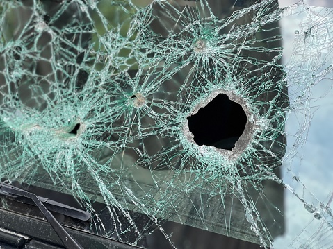 Bullet holes in the front safety glass of car. Car windshield shattered by gunshots.