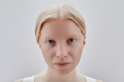 Closeup portrait of blonde girl looking at camera with intense face expression against white background