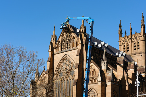 Part of an old church with a crane and deep blue sky behind.