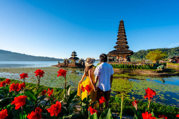 joven pareja turista relajándose y disfrutando de la hermosa vista en el templo ulun danu beratan en bali, indonesia - bali indonesia temple travel fotografías e imágenes de stock