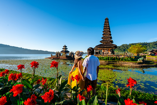 Young couple tourist relaxing and enjoying the beautiful view at Ulun Danu Beratan temple in Bali, Indonesia