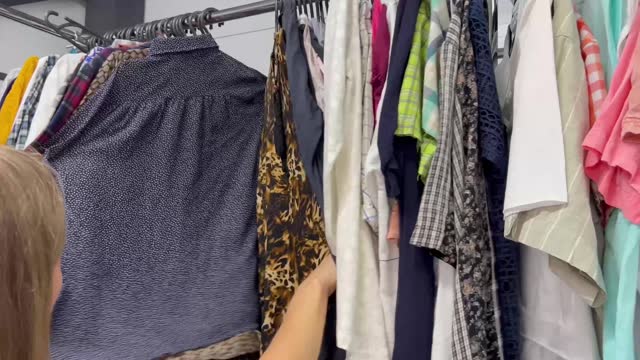 A woman chooses clothes in a second-hand store. Buying used clothes. Shooting medium plan