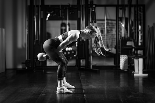 Pretty young woman slavic in sports uniform works out in evening in an old gym, doing stretching exercises in front of mirror. Concept of healthy lifestyle, sport and exercise in gym. Copy space