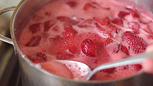 The process of making jam. remove the foam from the boiling strawberries