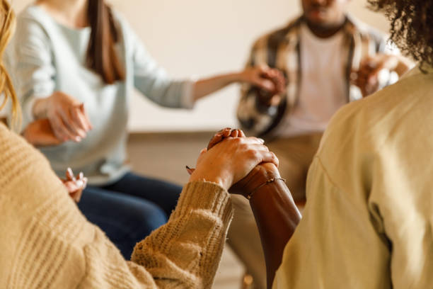 istock Diverse group of people sitting in circle and holding hands during a group therapy session 1503234478