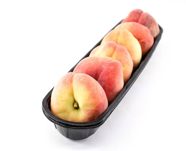 istock Flat peaches in a row on a narrow black plastic tray. 1503240008