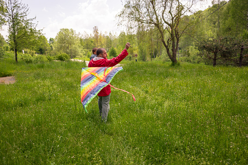 A silhouette of a child running and flying a kite.