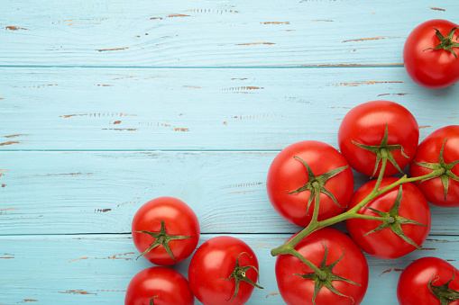Bunch of fresh tomatoes on blue background. Vertical photo. Top view