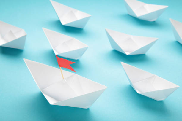 istock Leadership concept. Red leader paper ship leading among white on blue background. 1503249840