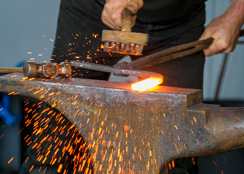 Sparks flying as a farrier works a red hot horseshoe on his anvil