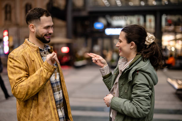As they walk hand in hand on the promenade, a young couple communicates with each other using sign language