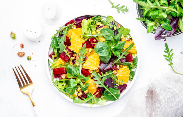 istock Beetroot and orange salad with arugula, lamb lettuce, mini chard and pistachios, white table, copy space.. Fresh useful dish for healthy eating 1503251101