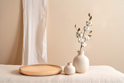 Beige ceramic vases with dry cotton branches. Stylish and minimalistic background for display your products in living room. Scandinavian interior. Modern home decor. Copy space.