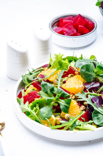 istock Beetroot and orange salad with arugula, lamb lettuce, mini chard and pistachios, white table, copy space.. Fresh useful dish for healthy eating 1503251140