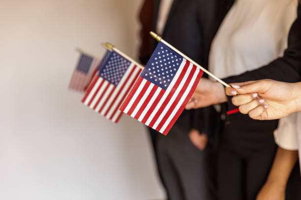 Midsection of unrecognizable group of people standing in line, holding American flags.