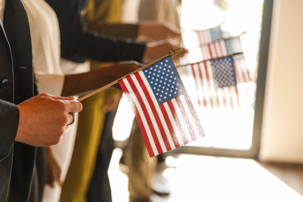 Midsection of unrecognizable group of people standing in line, holding American flags.