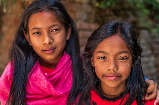 Portrait of two young Nepali sisters, they live in Bhaktapur. Bhaktapur is an ancient town in the Kathmandu Valley and is listed as a World Heritage Site by UNESCO for its rich culture, temples, and wood, metal and stone artwork.