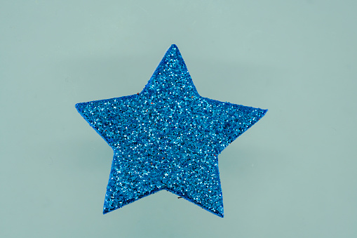 Blue glitter star on blue background. Christmas and New Year concept.
