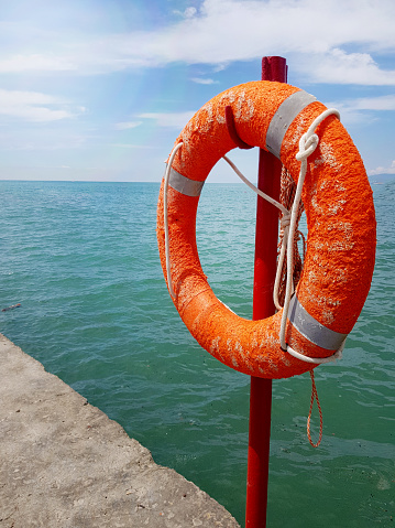 Lifebuoy on the background of the azure sea, sea pier in the sea, close-up, vertical.