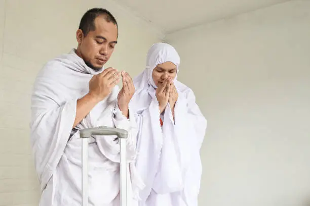 Indonesian couple praying dua before hajj and umrah, leaving home.