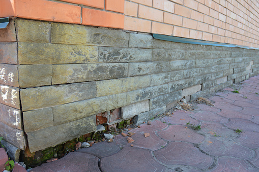 Mineral Efflorescence and wet foundation wall cracks - warning signs. House foundation repair. Broken wet foundation house brick wall.