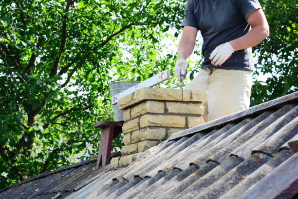 istock Chimney construction, repairs and re-building. A contractor is bricklaying a brick chimney on an house asbestos roof. 1503256066