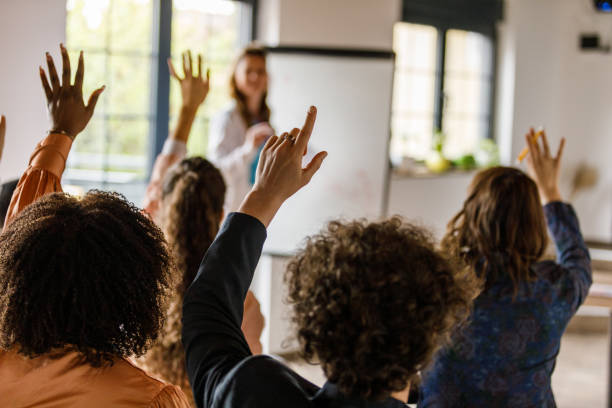 Businesswoman writing on whiteboard while holding a presentation for a group of business people Selective focus shot of young businesswoman writing data on a whiteboard while holding a presentation for a group of diverse, engaging business people. q and a stock pictures, royalty-free photos & images
