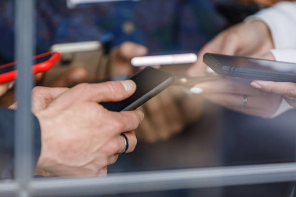 Group of business people standing by the window, using their smart phones stock photo