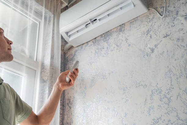 istock Young man switching on air conditioner at home for comfort temperature with remote controller in hot summer 1503260131