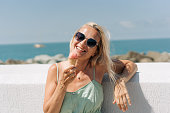 Cheerful carefree woman eats ice cream on the seashore on a hot summer day.