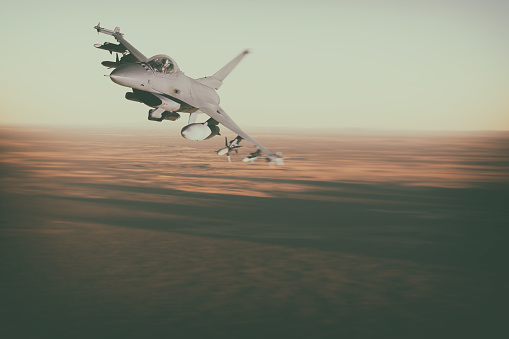 A modern F16 fighter jet streaks across the desert landscape. Scale model photography.