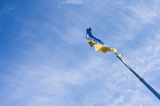 Flagpole with the Ukrainian flag against blue sky.