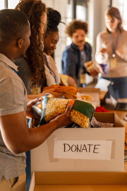 Diverse group of passionate volunteers work together to pack boxes of food and clothing for those in need, spreading love and support.