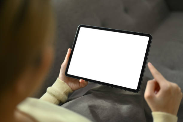 istock View over shoulder woman sitting on couch and using digital tablet. Empty screen for your advertising text message. 1503273726