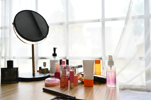 Round mirror, lotion bottle and skincare product on dressing table.