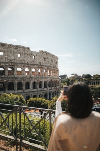 A young female photographer taking a picture of the iconic Colosseum in Rome