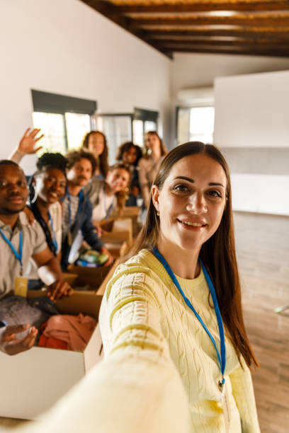 Group of diverse volunteers taking selfies together while preparing donations