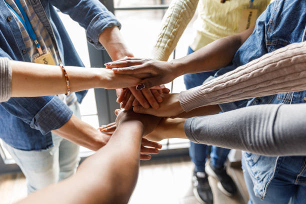 Close up shot of diverse hands stacked together in unity Close up shot of unrecognizable group of diverse individuals forming a united front, holding their hands stacked in a gesture of solidarity. non profit organization stock pictures, royalty-free photos & images