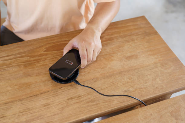 istock Charging mobile phone battery with wireless charging device in the table. Smartphone charging on a charging pad. Mobile phone near wireless charger Modern lifestyle technology concept. 1503283935