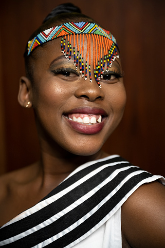 Close up portrait confident young woman wearing traditional beads smiling at camera