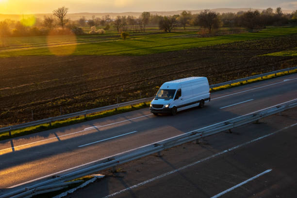 white delivery van on the highway. white modern delivery small shipment cargo courier van moving fast on motorway road to city urban suburb. the world's best transport of goods. - delivery van imagens e fotografias de stock